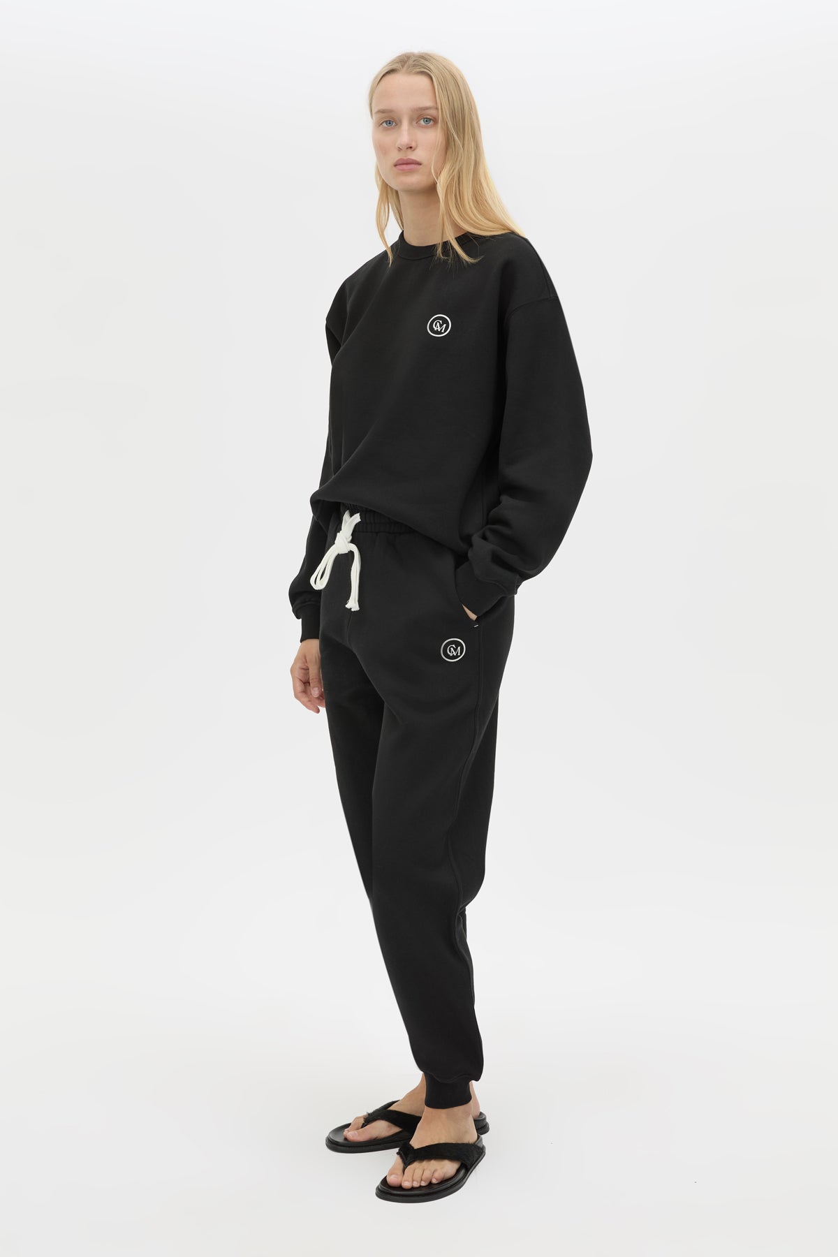 3/4 view CAMILLA AND MARC Bonnie relaxed logo track pant in black with elasticated drawcord waistband.
