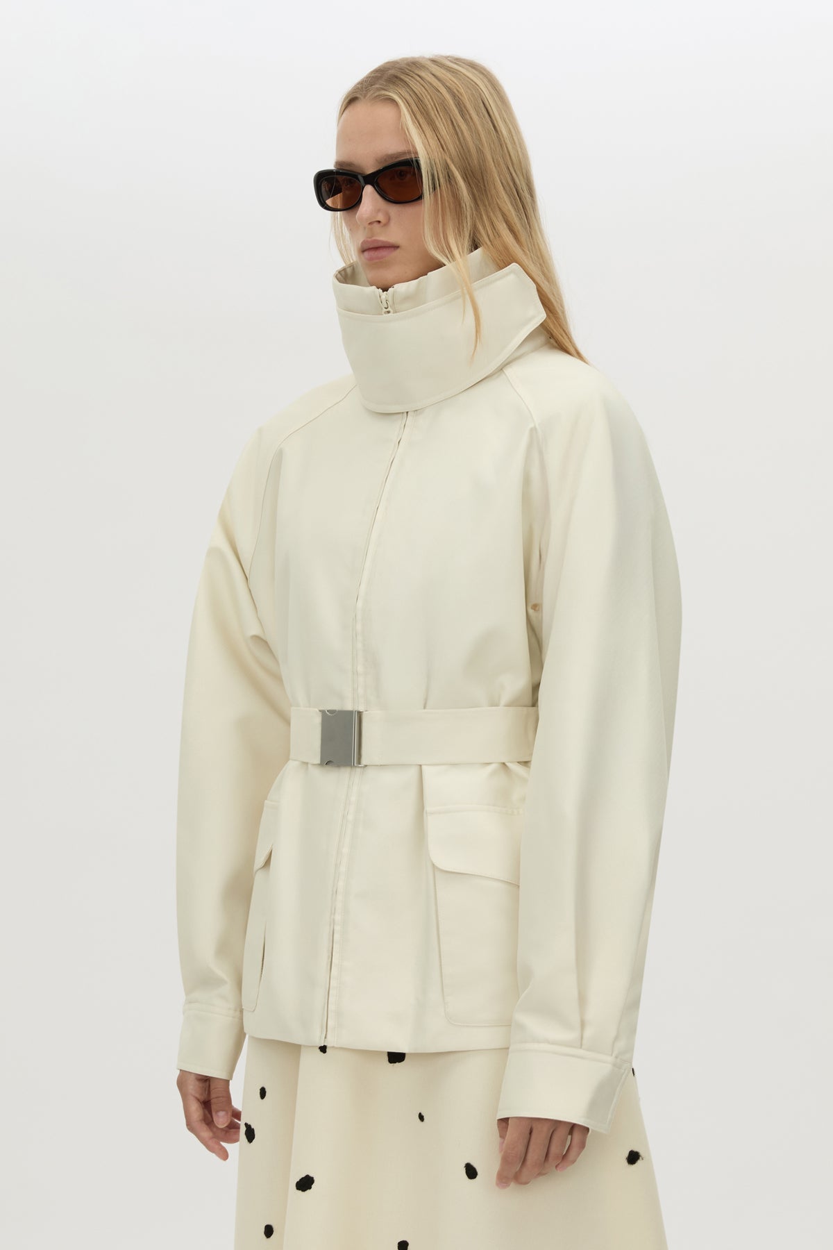 3/4 view CAMILLA AND MARC Drea funnel neck puffer jacket in cream with utility waistbelt and detachable throat latch.