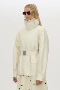 3/4 view CAMILLA AND MARC Drea funnel neck puffer jacket in cream with utility waistbelt and detachable throat latch.