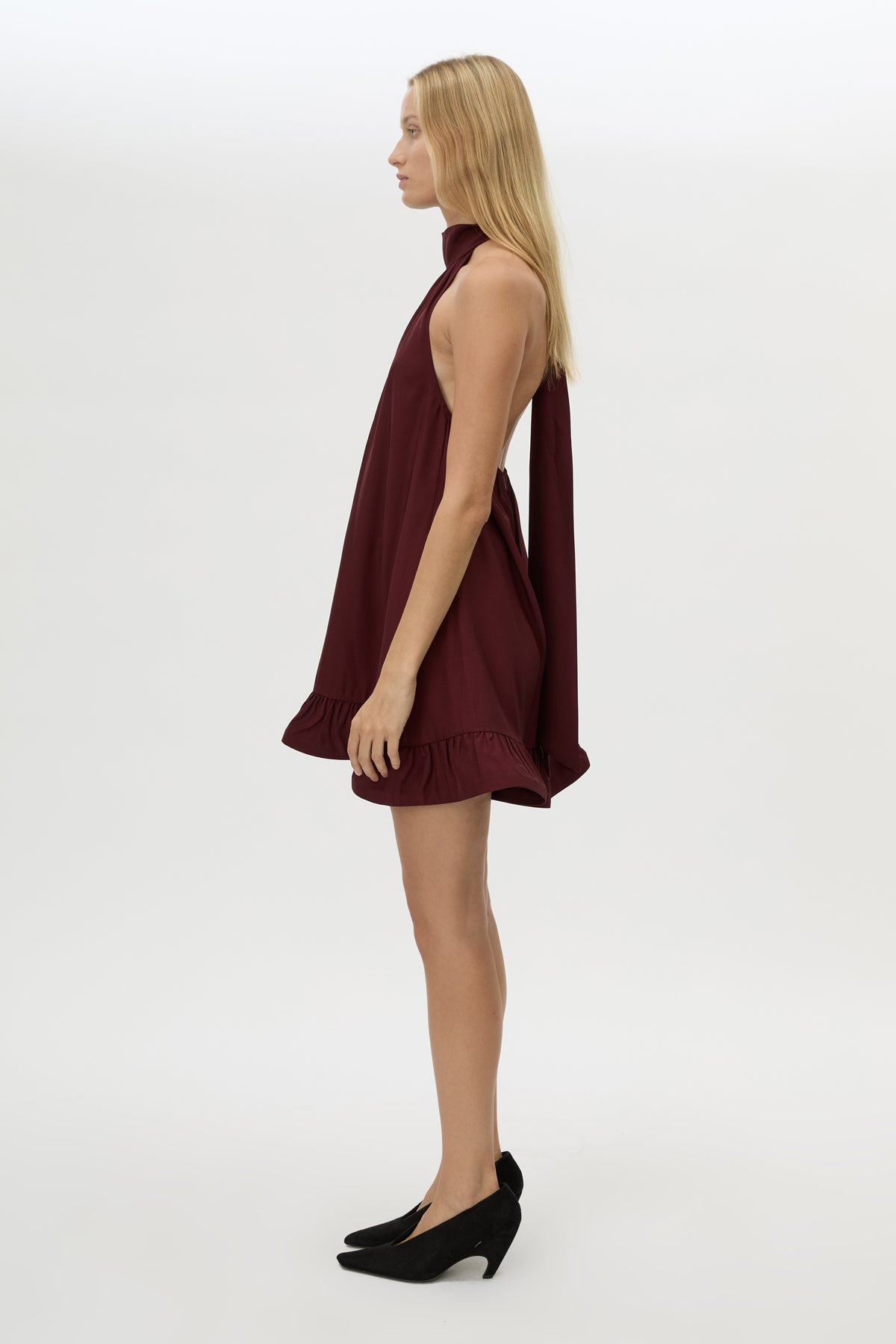 Side view CAMILLA AND MARC Elsen Halter Mini Dress in Burgundy with open back, tie‑up neck and fluted crinoline hem.