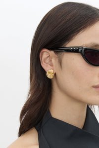 Model view CAMILLA AND MARC Odin Earrings 18k gold-plated geometric knot earrings.