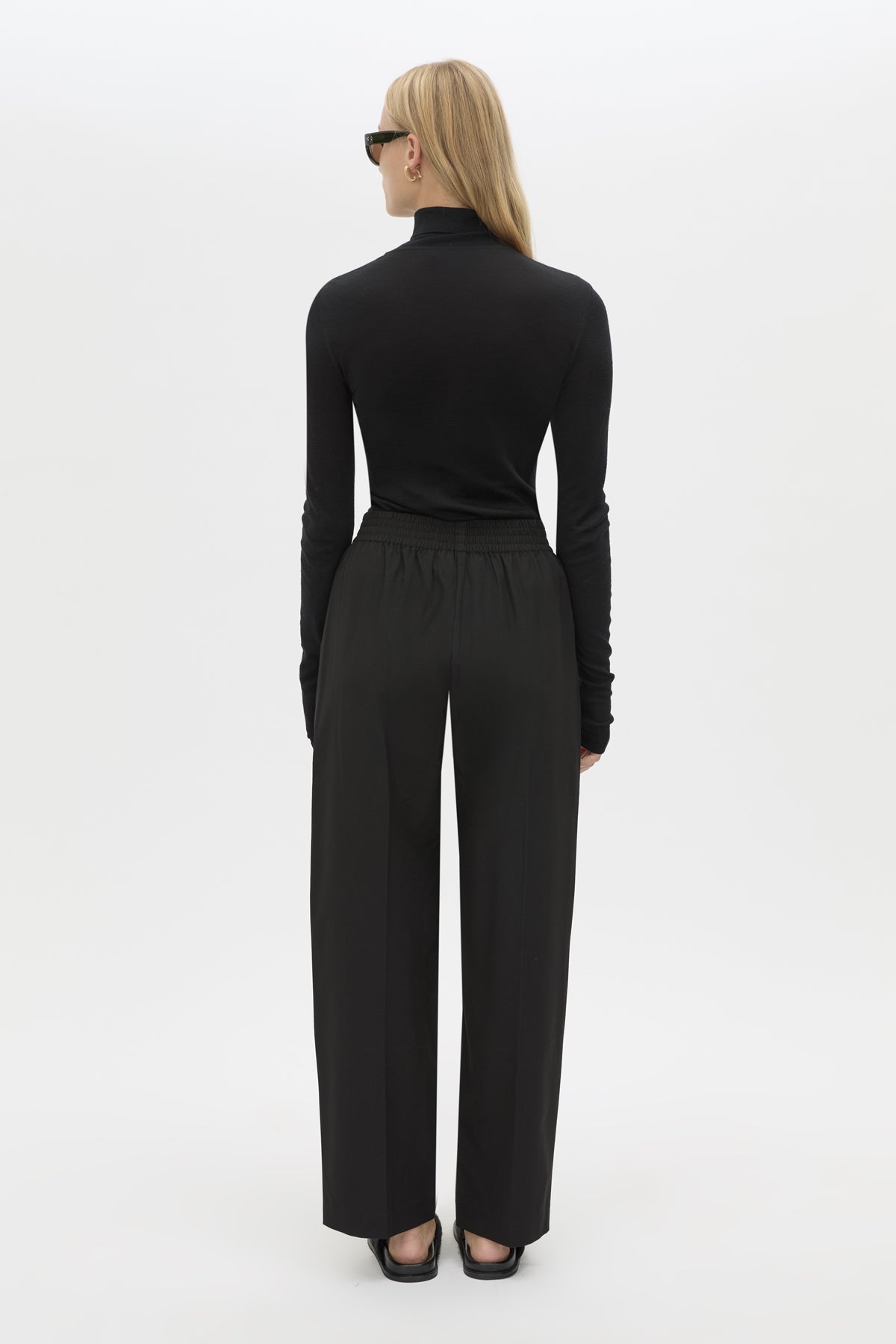 Back view CAMILLA AND MARC Sylvia soft suiting high-waisted pant in black with monogram patch at waistband.